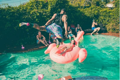 man-jumping-into-pool-with-pink-flamingo-inflatable